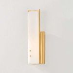 Lucio Wall Sconce lit with warm light casting soft glow on alabaster shade