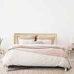 Styled bedroom scene with the bed made up in soft pink and white linens and pillows