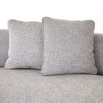 Side detail of thick cushions layered on curved corner seating area