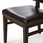 Close-up of padded black leather seat cushion showing smooth leather texture and oak frame edges
