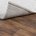 Corner flipped over showing textured woven backing and edge detailing on hardwood floor