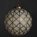 Polyhedron Pendant illuminated with soft light against dark charcoal wall, showing brass frame and white glass
