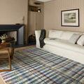 Humphrey Plum rug in living room setting with beige couch, armchair, and dark fireplace