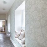 Rachel Ashwell Stipple wallpaper installed on hallway walls featuring decor with pillows and window seat
