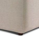 Bottom corner detail showing short round wooden leg and tight seam of upholstery fabric