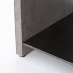 Close-up of the corner where the dark grey concrete frame meets the black metal shelf