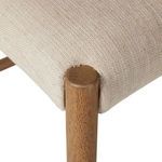 Close-up of rounded stool leg nestled into the natural light woven fabric seat corner