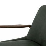 Detail of wooden armrest with soft curve next to green leather backrest