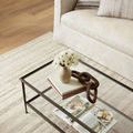 Close-up view of rug underneath glass coffee table and beige sofa showing fine texture and soft colors