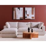 Wide room view with Folke round coffee table centered on a light rug in front of a beige sofa and artwork