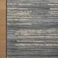 Corner of rug on wooden floor highlighting fringe and textured linear pattern