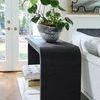 Side angle repeating view with indoor plant in textured black and white pot on console table near white sofa