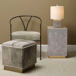 Square hide-on-hair ottoman with cushioned top, ribbed sides, and antique brass base in a neutral room setting