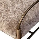 Close-up showing the iron arm joining the amber ash leg with cream shearling upholstery