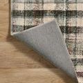 Close-up corner of Humphrey Forest rug flipped, displaying the light gray woven backing