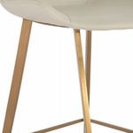 Close-up on gold iron legs and footrest with white faux leather upholstery stitching