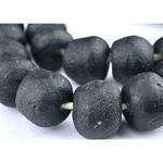 Extreme close-up of black sea glass beads showing rough matte texture and small scratched areas