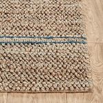 Detailed corner view of dense jute loops with blue stripes on hardwood floor