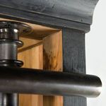 Close-up of top corner of Ivy Bookcase showing curved molding, black hand-rubbed finish, and iron hardware
