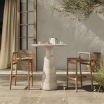 Second patio scene showing outdoor bar table with small teak chairs and greenery in background