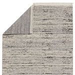 Rug flipped to show tightly woven gray and cream backing with fringe