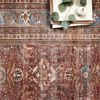 Close-up of vintage-style rug showing detailed floral motifs and texture with books and eucalyptus leaves on top