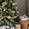 Close-up of crackled olive green mercury glass ornaments on Christmas tree surrounded by natural dried orange garlands and...