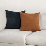 Two throw pillows on beige sofa, one in brown basket weave suede and one in dark navy blue