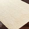 Close view of the flat woven texture and edges of the Calla Butter Handmade Rug on hardwood floor