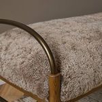 Close-up of iron arm and shearling upholstery in warm room setting