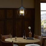Pendant hanging over round table in a warmly lit room with wood paneling and leather chairs