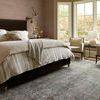 Closer angled bedroom view showing Jules Emerald rug under bed and seating by windows with natural wood flooring