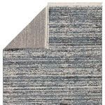 Back corner of rug folded to show textured woven backing and cream fringe