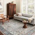 Bianca rug styled in a living room with gray sofa, wooden chair, and large window natural light