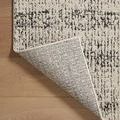 Rug corner flipped over exposing detailed woven backing and edge stitching on wood floor