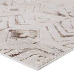 Close-up angled view showing texture and pile height of cream and taupe geometric rug pattern