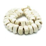 Angled view of faceted white cow bone beads showing texture and rounded square shapes with rough natural edges