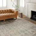 Rug shown in a living room under a tufted caramel leather sofa with wood flooring and white walls
