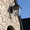 Lantern mounted on stone exterior wall under bright daylight with visible shadow