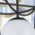 Close-up of black metal joint connecting frame bars above the milky white glass globe