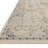 Low angled close-up of rug corner showing detailed border design and texture on a light beige foundation