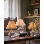 Three table lamps on rustic wooden table in living room: one natural fabric shade, white scalloped shade, and green scallo...