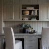 Galvanized tray with brass rim holding decor items on grey desk surrounded by beige cabinetry and chairs