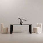 Two cream rolling dining chairs flanking a dark dining table with a decorative vase