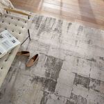 Top view of rug beside bench with shoes, showing distressed taupe and cream pattern with textured weave