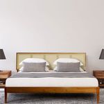 Styled king bed in bedroom with white bedding, grey pillows, wooden side tables and lamps