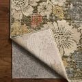 Corner lifted to reveal woven backing and rug pad underneath on wood floor