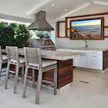 Three Laguna Counter Stools with light beige cushions at outdoor bar with kitchen setup