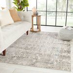 Kenrick Floral Gray/Light Blue rug styled in a modern room setting under a light tufted sofa and decorative pouf