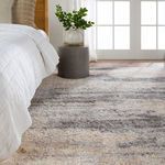 Bedroom corner with rug placed beside bed and round concrete side table with plant near bright window